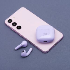 Fioletowe słuchawki bezprzewodowe Blue Star w etui ładującym na różowym smartfonie.